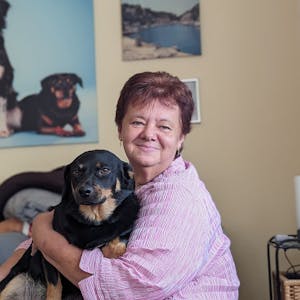 Eine Frau mit ihrem Hund in ihrem Wohnzimmer vor einem Hundefoto.