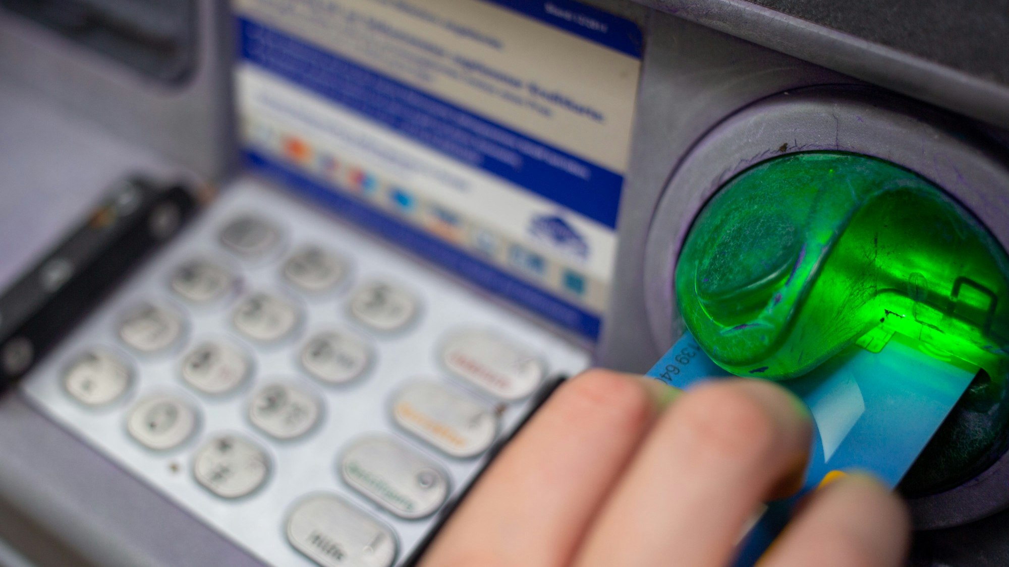 Eine Bankkundin steckt ihre Girokarte in einen Geldautomaten.