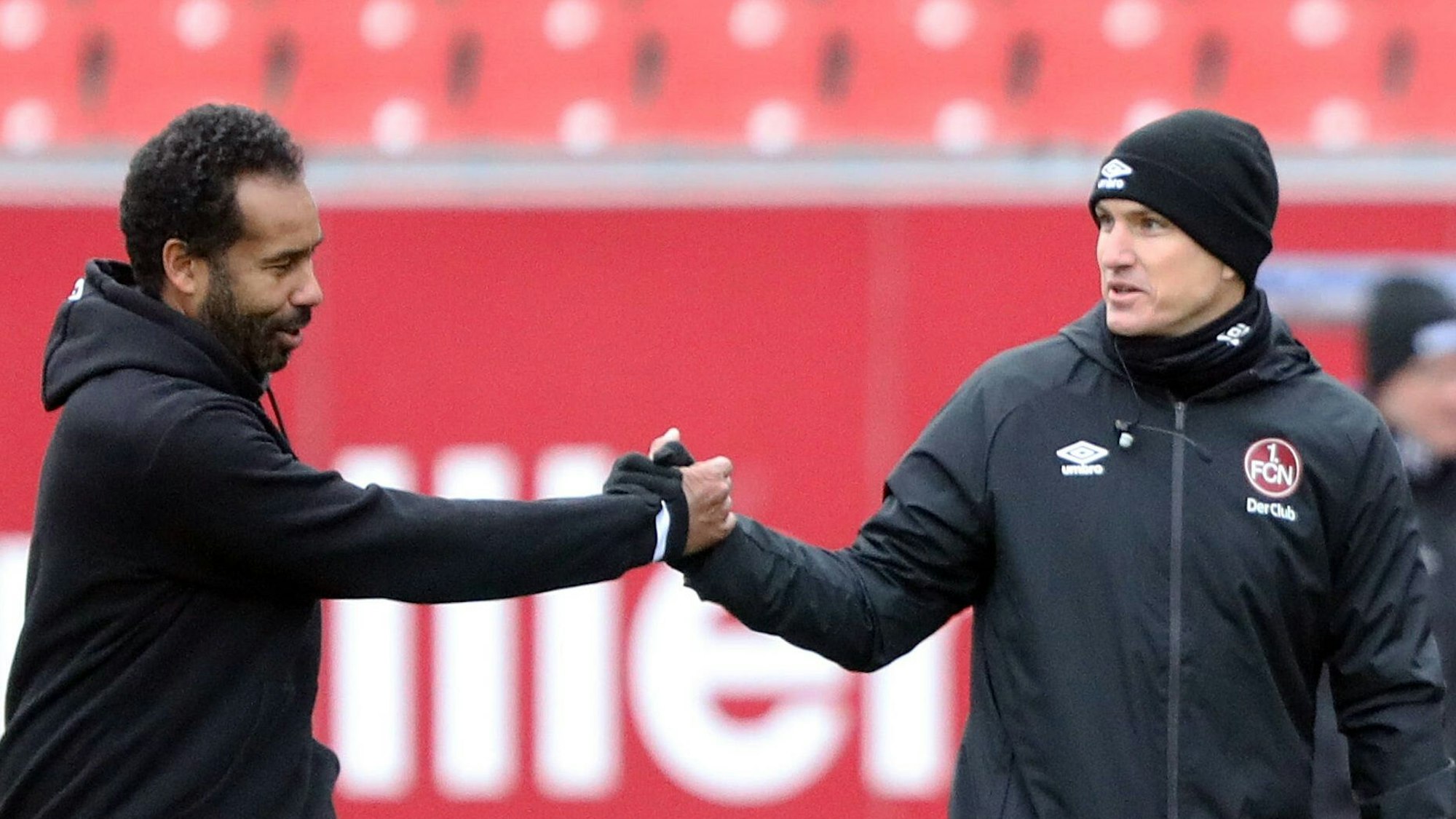 Hamburgs Trainer Daniel Thioune und Nürnbergs Coach Tobias Schweinsteiger klatschen an der Seitenlinie ab.