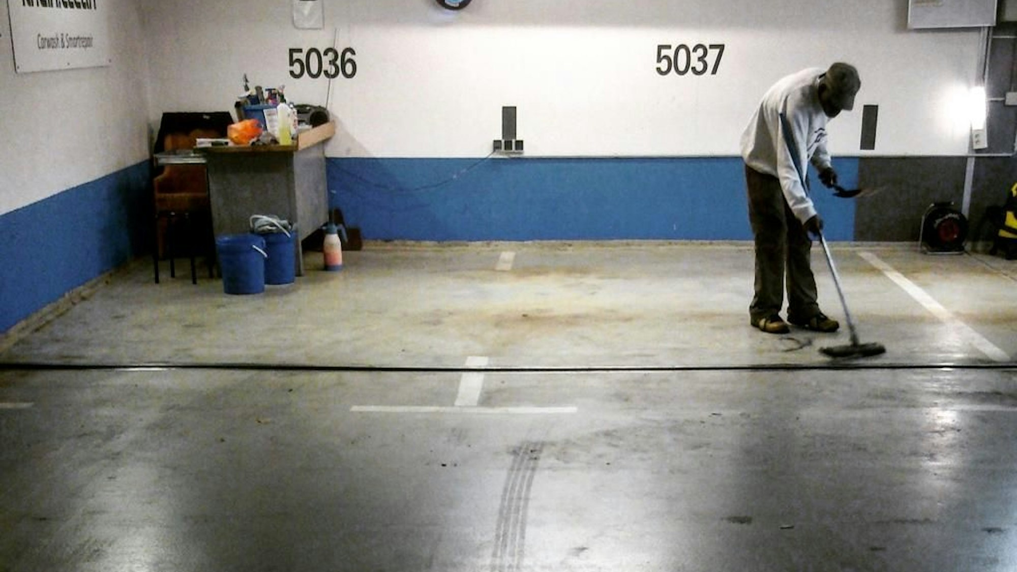 Ein Mann reinigt Parkplätze in einer Tiefgarage.