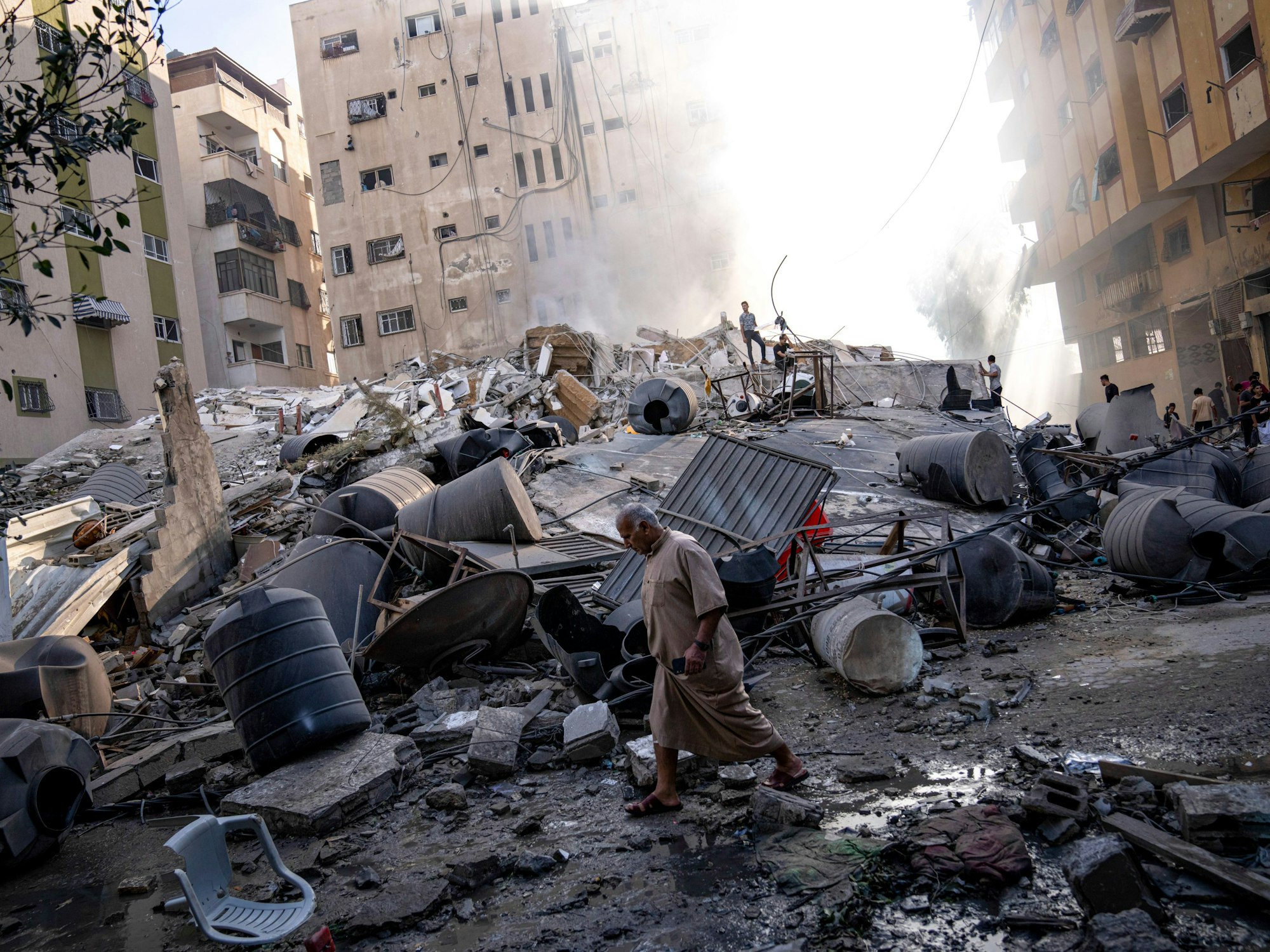Palästinensisches Gebiet, Gaza-Stadt: Menschen laufen durch die Trümmer eines Gebäudes, nachdem es bei einem Luftangriff zerstört wurde. Die im Gazastreifen herrschende islamistische Hamas, die von Israel, der EU und den USA als Terrororganisation eingestuft wird, hatte am Samstag (7. Oktober 2023) den Beginn einer Militäroperation gegen Israel verkündet.