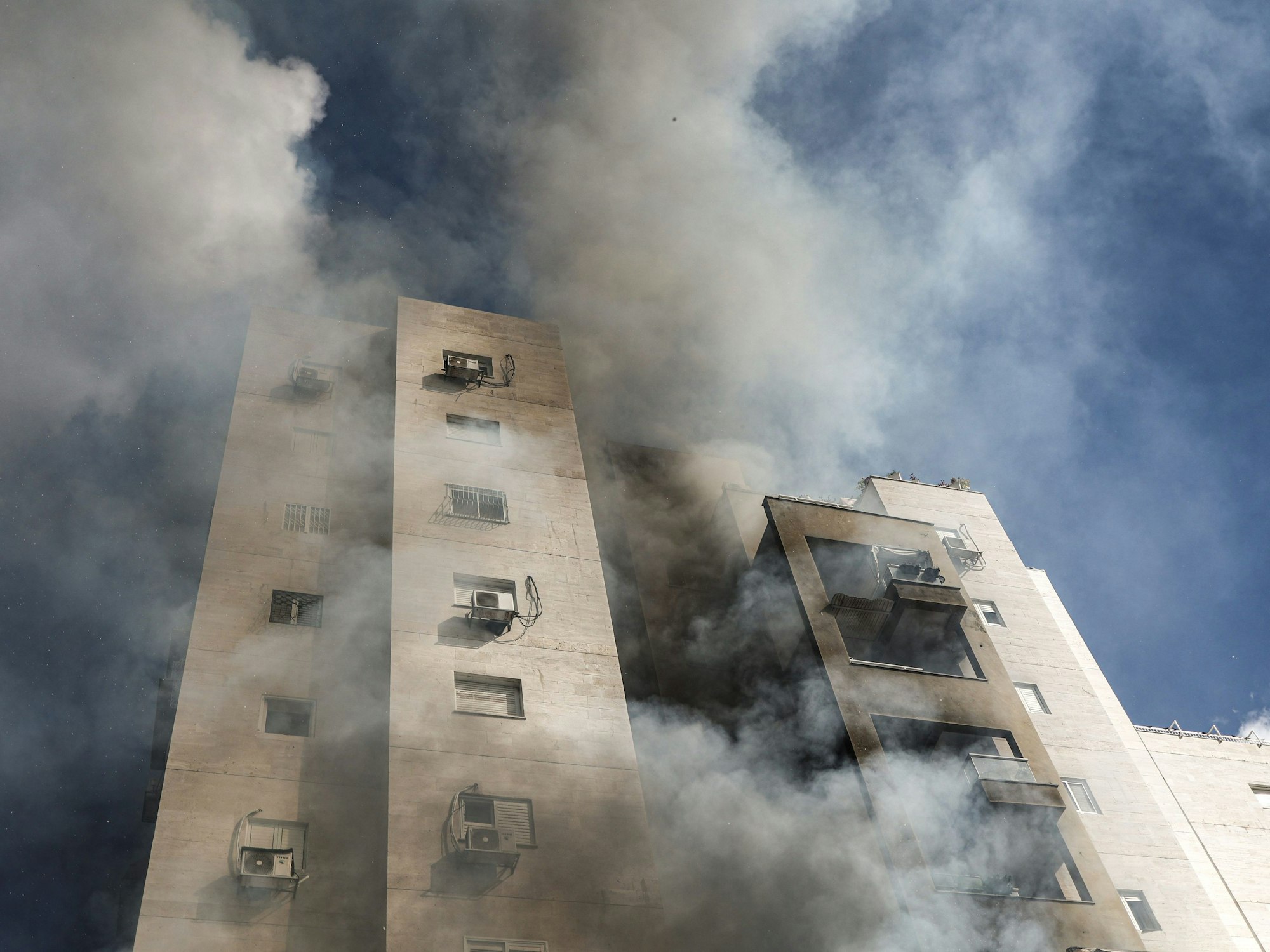Nach einem Raketenangriff aus dem Gazastreifen ist Rauch aus einem Wohnhaus in Aschkelon (Israel) zu sehen. Nach massiven Angriffen aus dem palästinensischen Gazastreifen auf Israel hat die israelische Armee am Samstag den Kriegszustand erklärt.