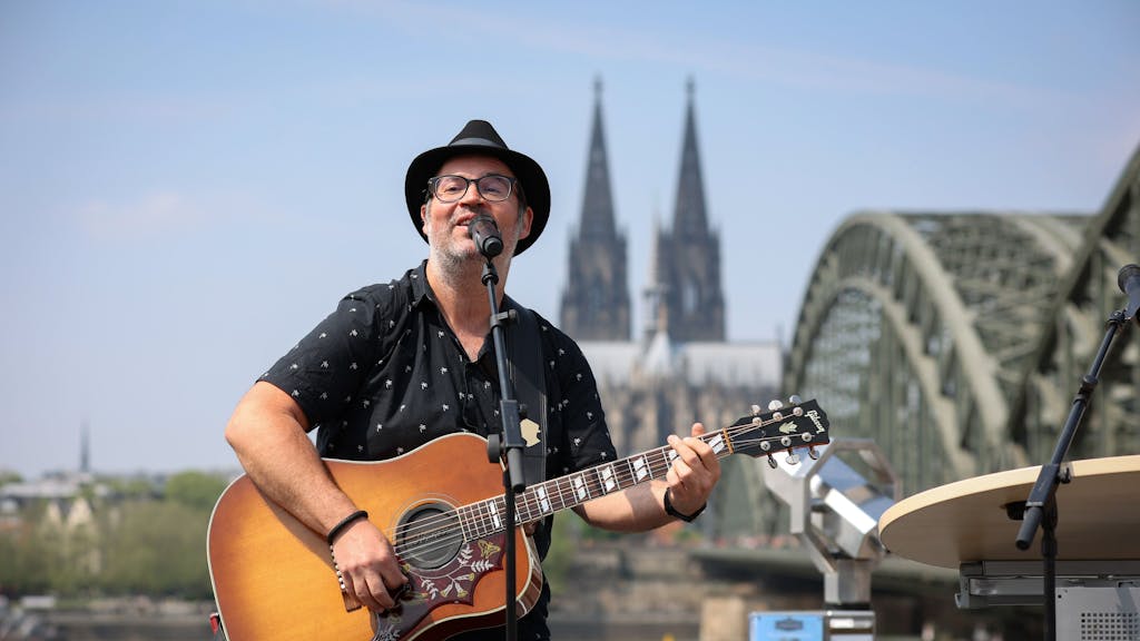 Björn Heuser singt mit seiner Karriere am Rhein vor dem Panorama von Dom und Hohenzollernbrücke.