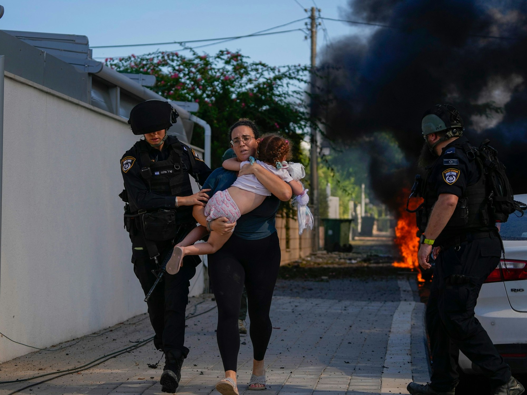 Israelische Polizeikräfte evakuieren am 7. Oktober 2023 in Aschkelon (Israel) eine Frau und ein Kind von einem Ort, der von einer aus dem Gazastreifen abgefeuerten Rakete getroffen wurde.