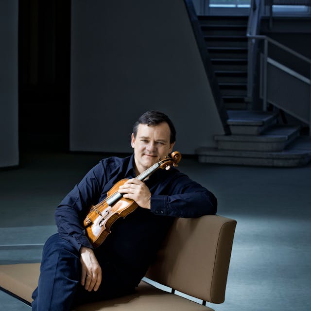 Frank Peter Zimmermann sitzt mit Geige auf einem Stuhl.&nbsp;