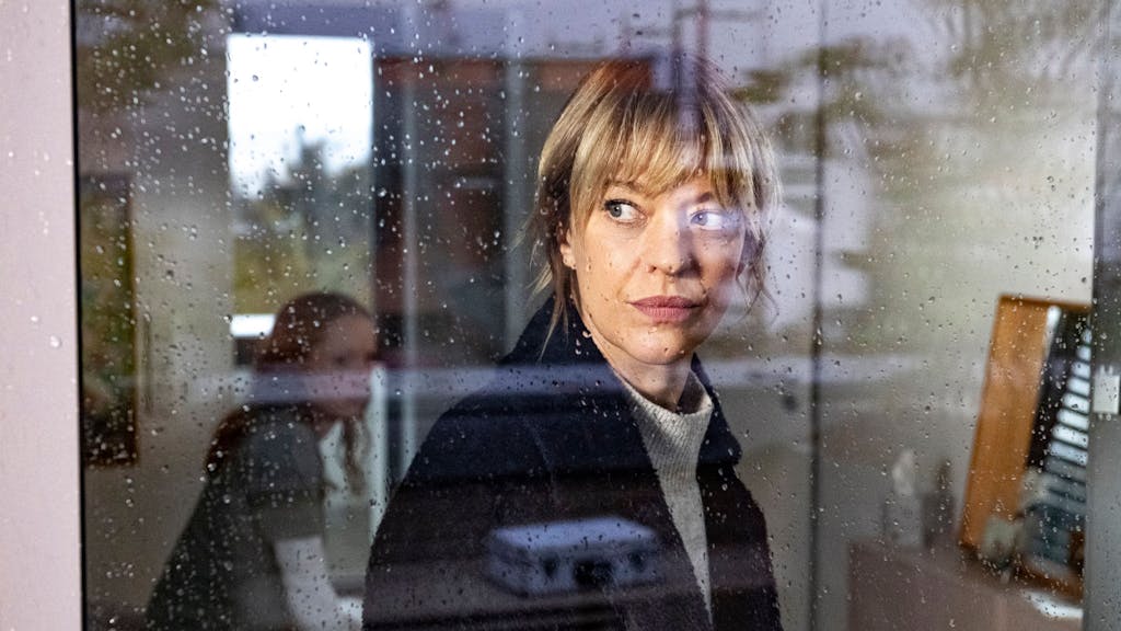 Ellen Berlinger (Heike Makatsch) schaut durch ein Fenster, auf dem Regentropfen zu sehen sind.