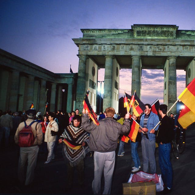 Menschen feiern mit Deutschland-Fahnen die deutsche Einheit vor dem Brandenburger Tor.&nbsp;