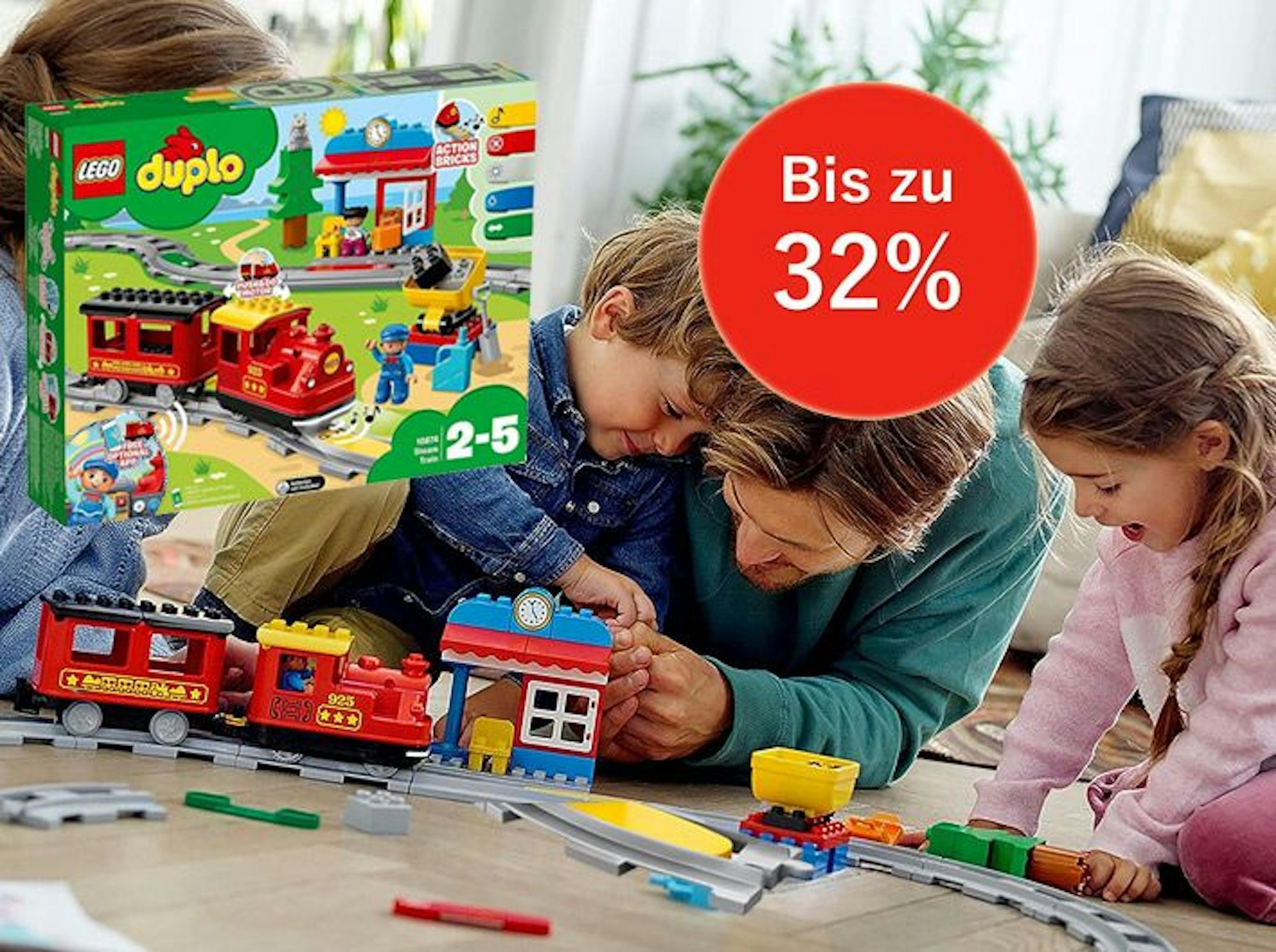 Auf dem Bild ist eine Familie zu sehen, die mit der Lego Duplo Eisenbahn spielt.
