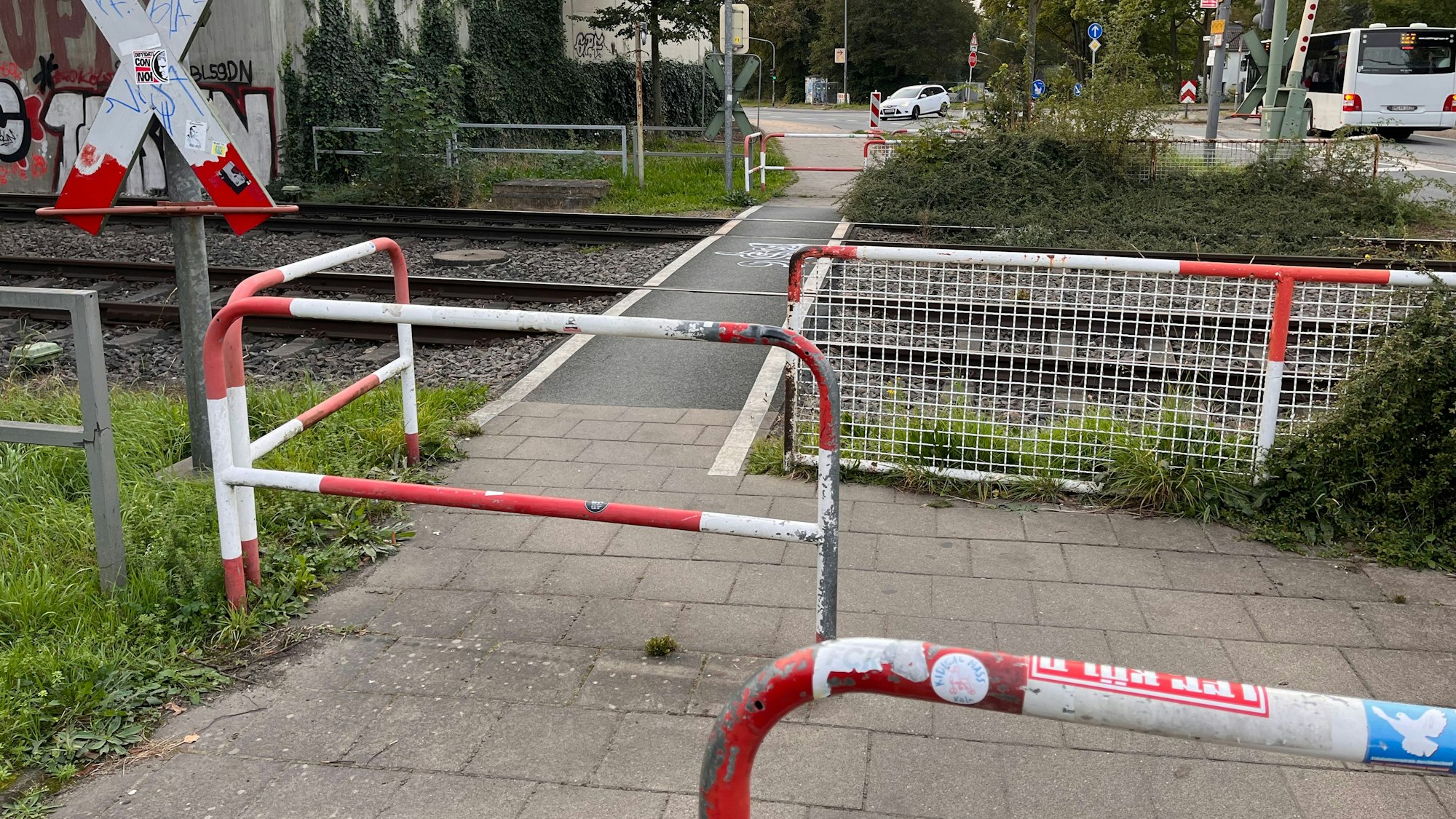 Am Bahnübergang an der Butzweilerstraße teilen sich Fußgänger und Fahrradfahrende einen Weg mit Drängelgittern.
