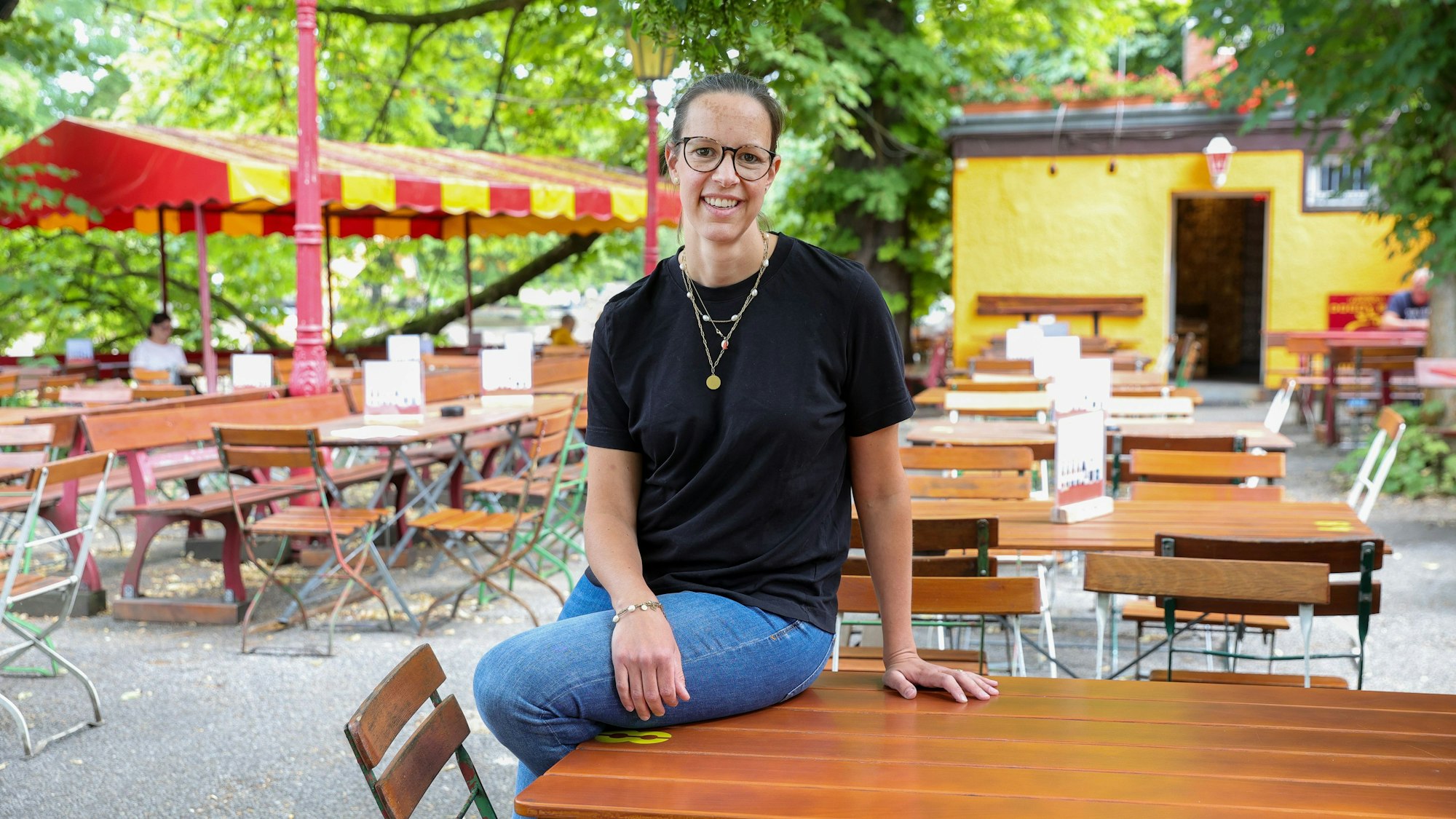Hellers Chefin Anna Heller sitzt auf einem Tisch im Biergarten am Volksgarten.



