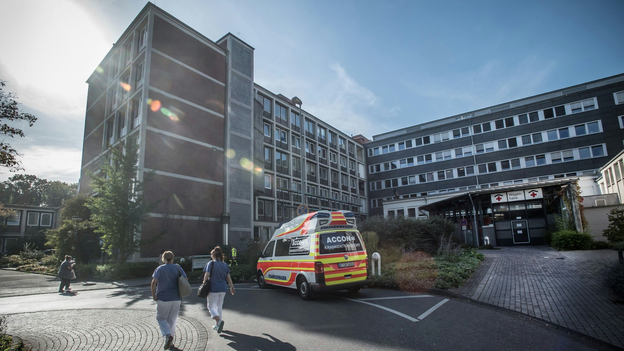 Die Notfallambulanz des Klinikums Leverkusen von außen, ein Rettungswagen steht davor, zwei Pflegerinnen sind von hinten zu sehen.