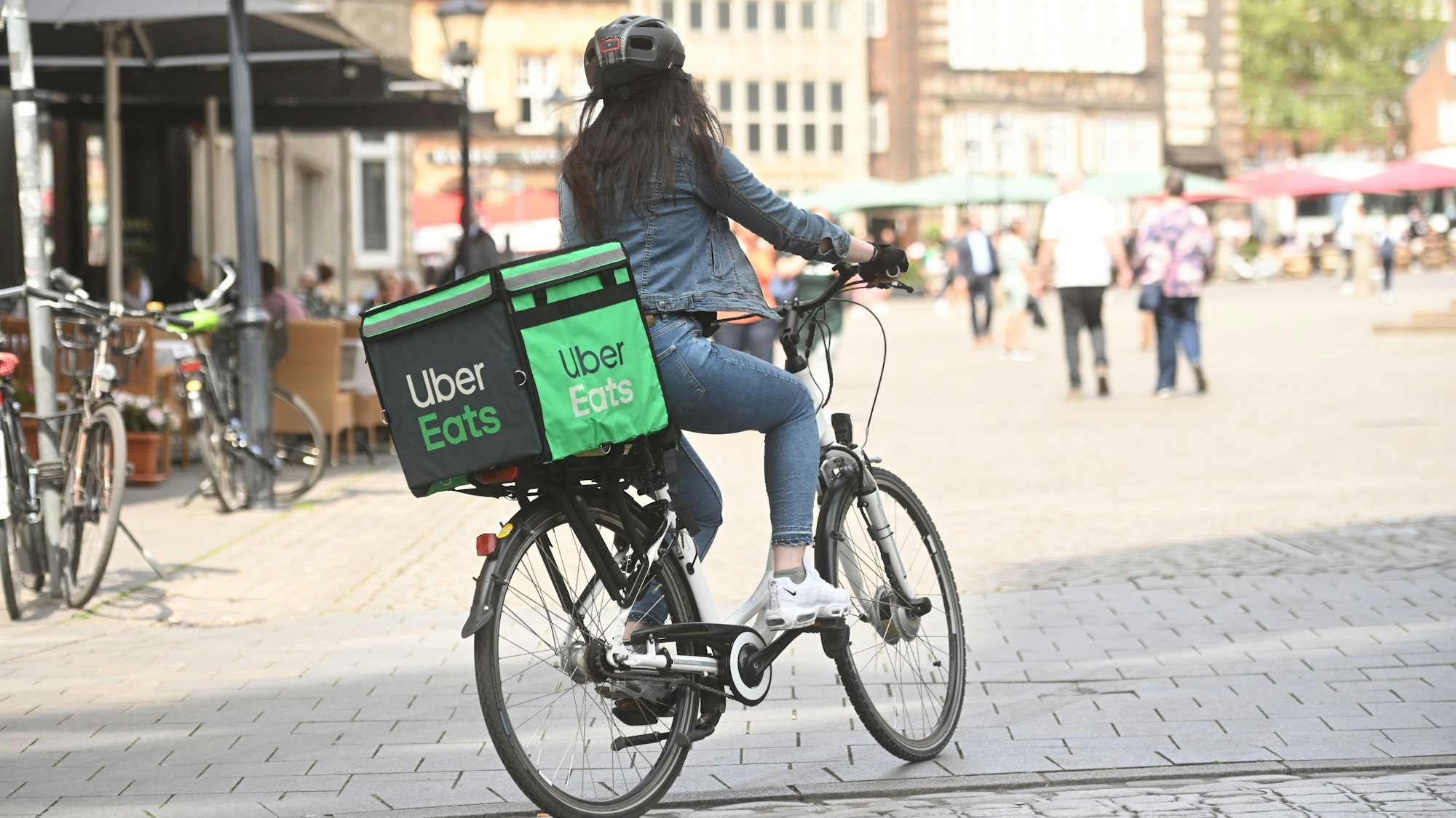 Eine Lieferantin fährt auf einem Fahrrad mit Uber Eats Gepäcktasche.