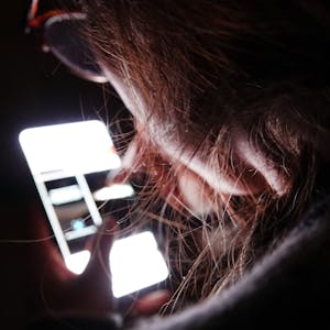 Ein Kind schaut im Dunkeln auf ein Handybildschirm.