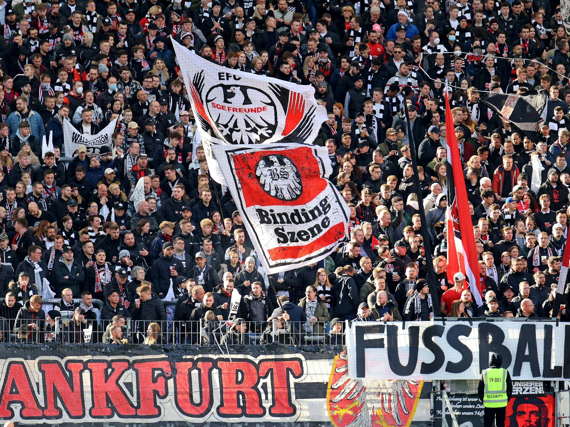 In der Frankfurter Fankurve werden Fahnen geschwenkt. Im Vordergrund eine Eintracht-Fahne mit der Aufschrift „Binding Szene“.