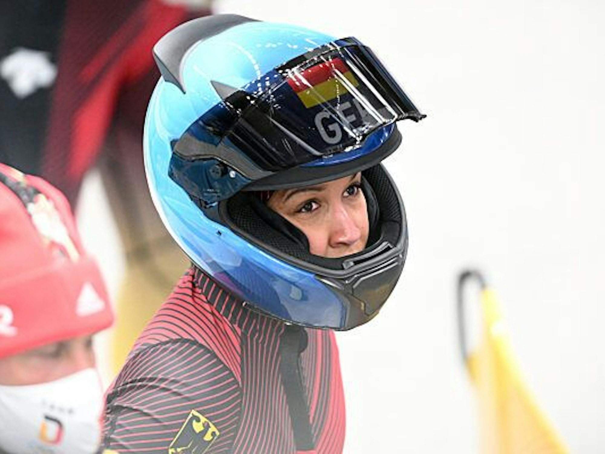 Eine Bobfahrerin im Deutschland-Teamkleidung bereitet sich auf die nächste Runde vor. Es ist nur ein Teil ihres Gesichts durch den Helm zu erkennen.