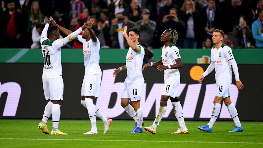 Die Spieler von Borussia klatschen sich nach einem Tor gegenseitig ab. Im Hintergrund feiern die Fans.
