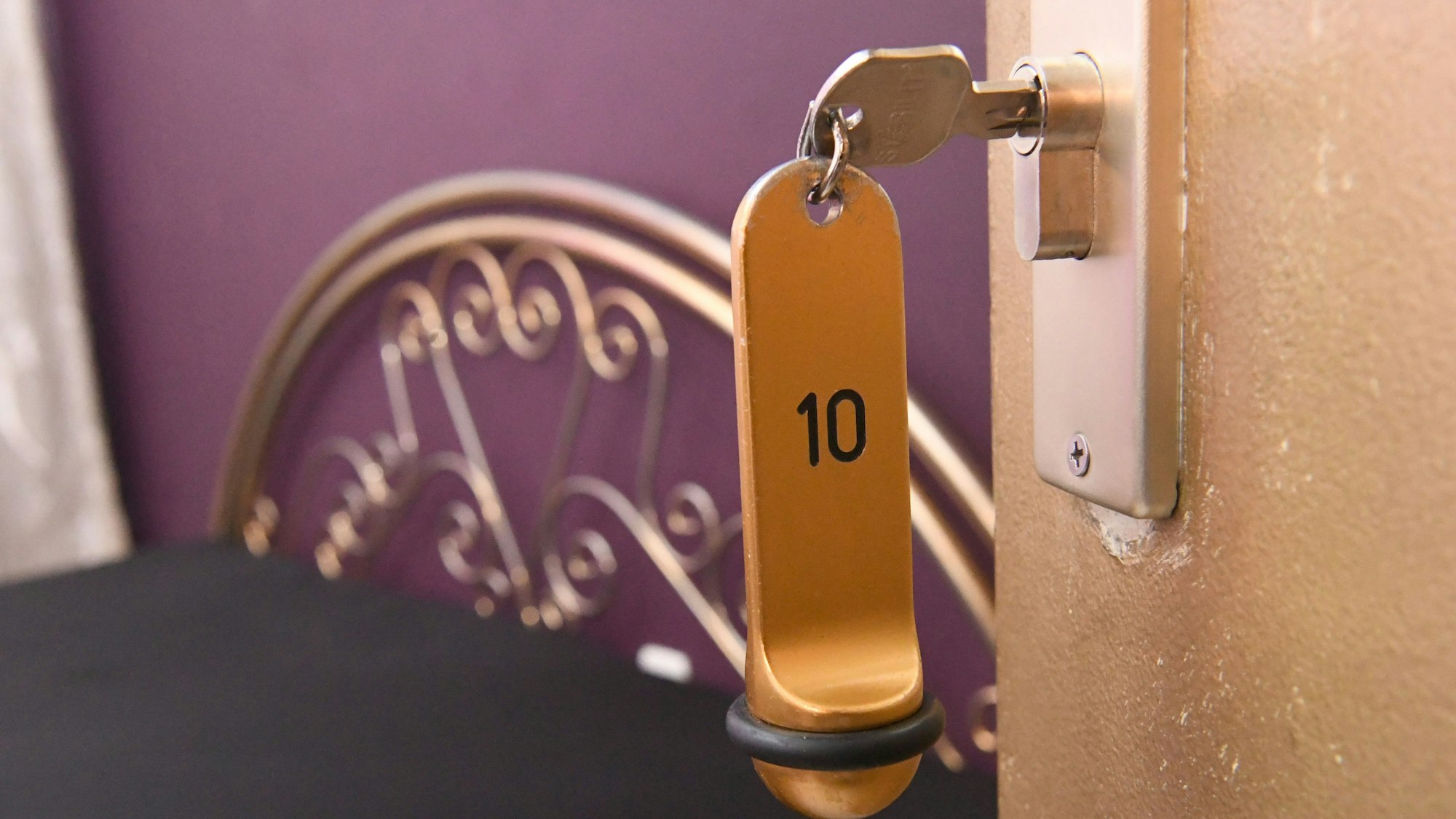 Ein Zimmerschlüssel hängt in einem Schloss an einer Zimmertür.