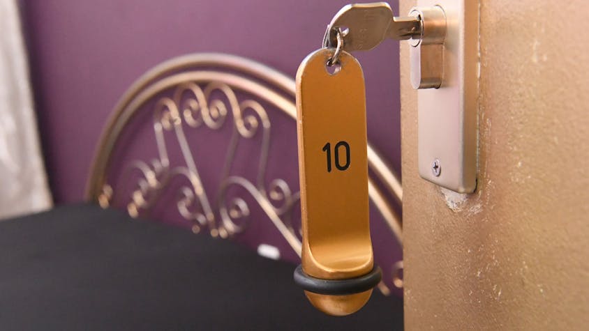 Ein Zimmerschlüssel hängt in einem Schloss an einer Zimmertür.&nbsp;