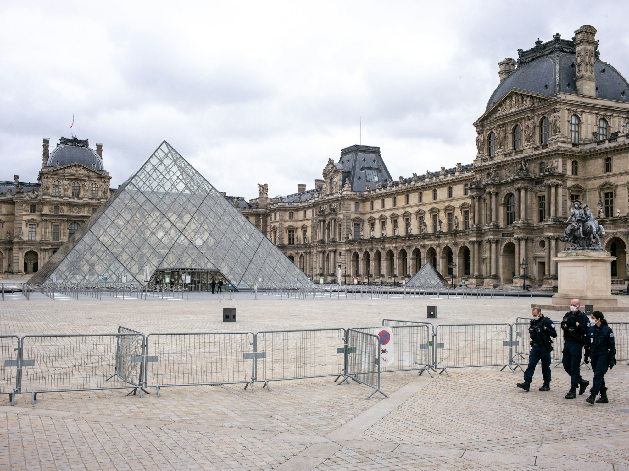 Der Louvre ist geschlossen, der Platz davor ist leer. Nur drei Polizisten gehen an einer Absperrung entlang.
