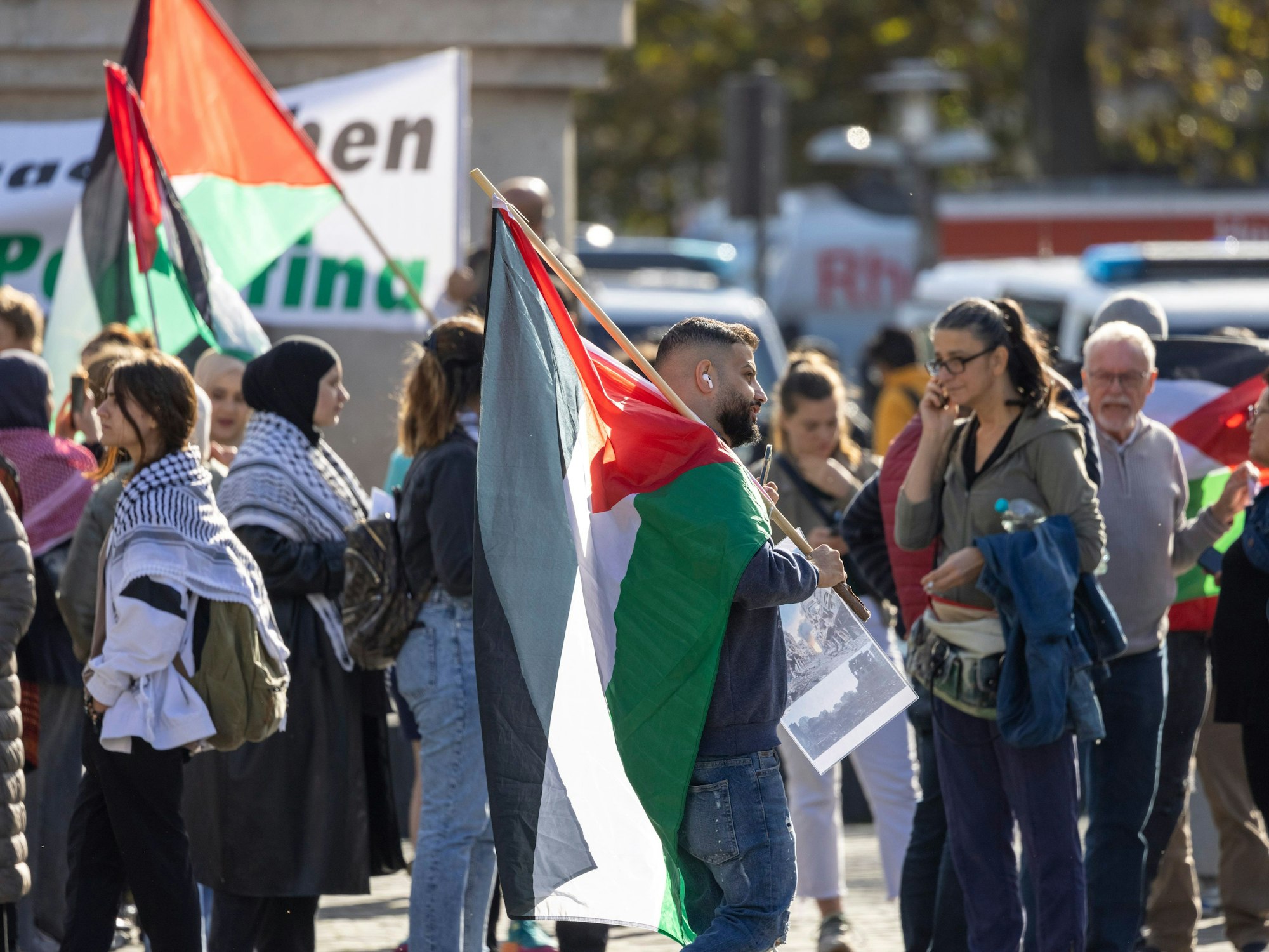 Teilnehmer und Teilnehmerinnen einer Kundgebung unter dem Motto „Palästina unter Besatzung“ stehen mit Fahnen auf dem Kölner Heumarkt.