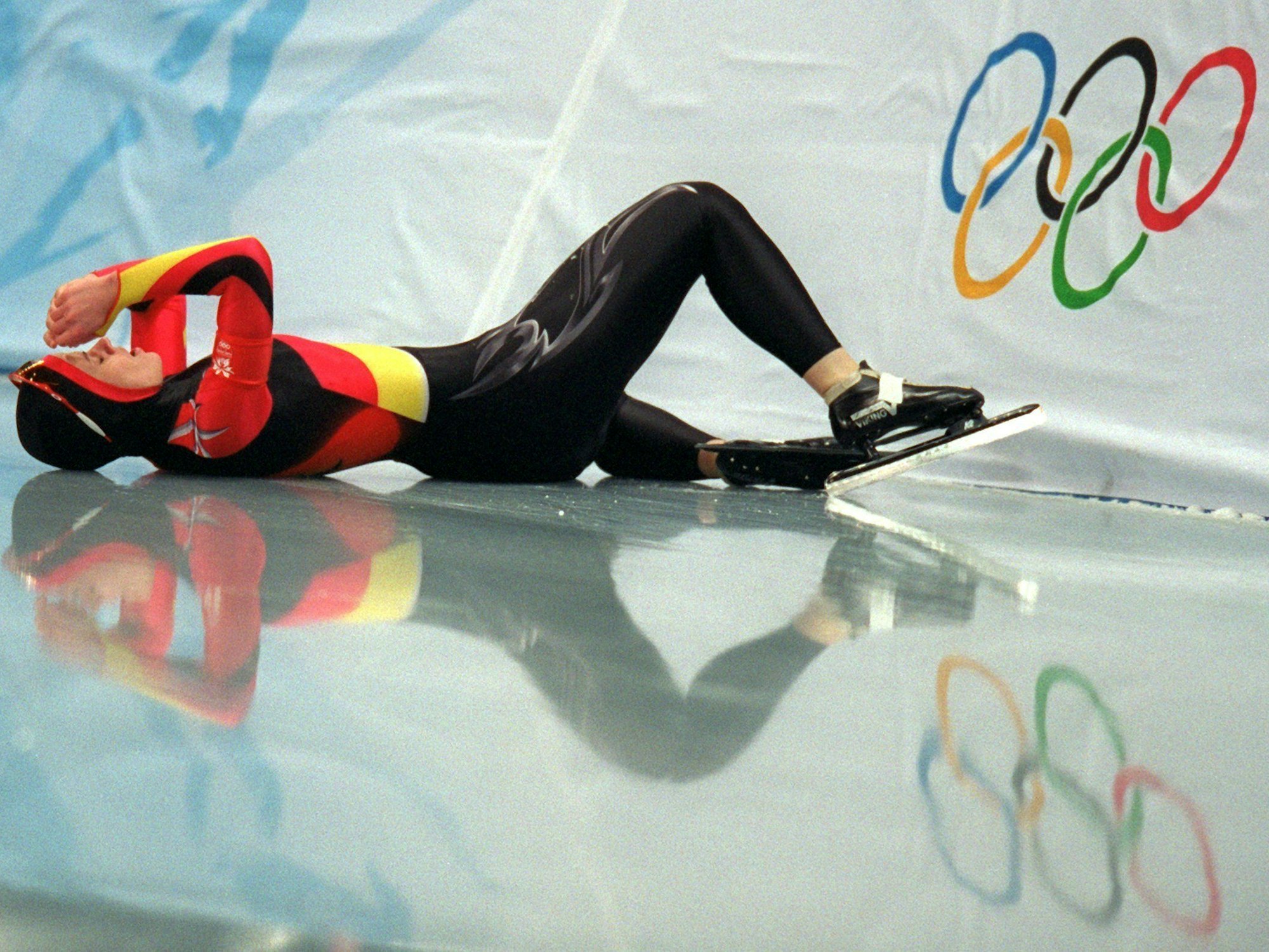 Eine Eisschnellläuferin liegt nach einem Sturz bei den Olympischen Spielen enttäuscht auf der Eisbahn.