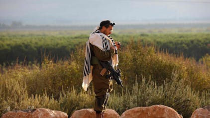 Ein israelischer Soldat, der Tefillin (Phylakterien) trägt, eine kleine schwarze Lederschatulle, die Pergamentrollen mit Versen aus der Tora enthält, betet am 15. Oktober 2023 in einer Militärposition im Norden Israels nahe der Grenze zum Libanon.