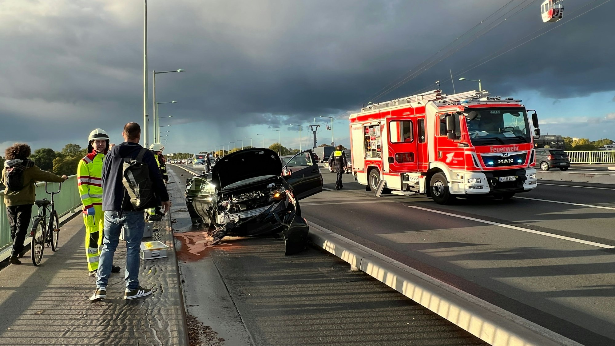 Ein verunfalltes Auto ist auf dem  Radstreifen auf der Kölner Zoobrücke gelandet. Im Hintergrund steht ein Feuerwehrauto auf der Fahrbahn.