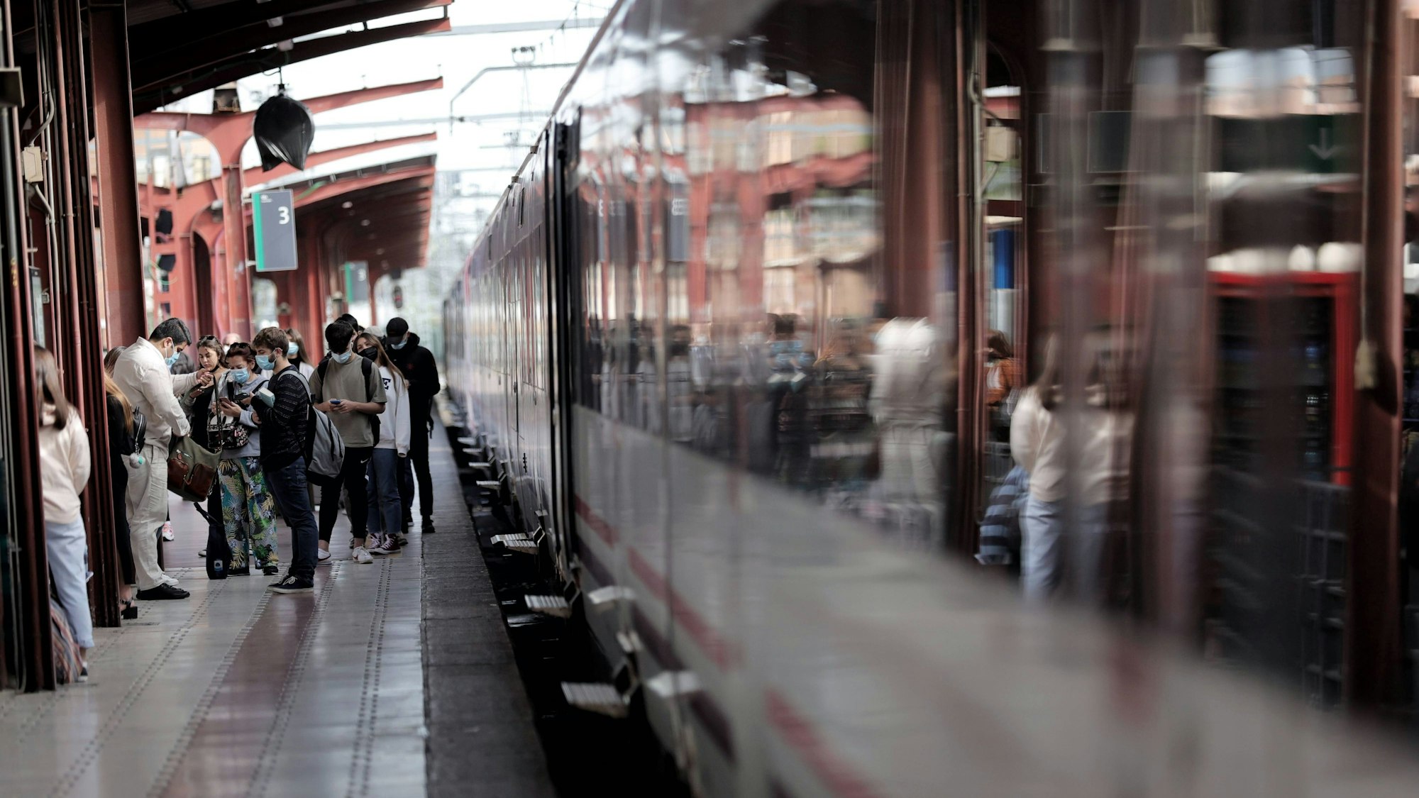 Fahrgäste stehen am Bahnsteig in Madrid neben einem Zug der spanischen Bahn-Gesellschaft Renfe.
