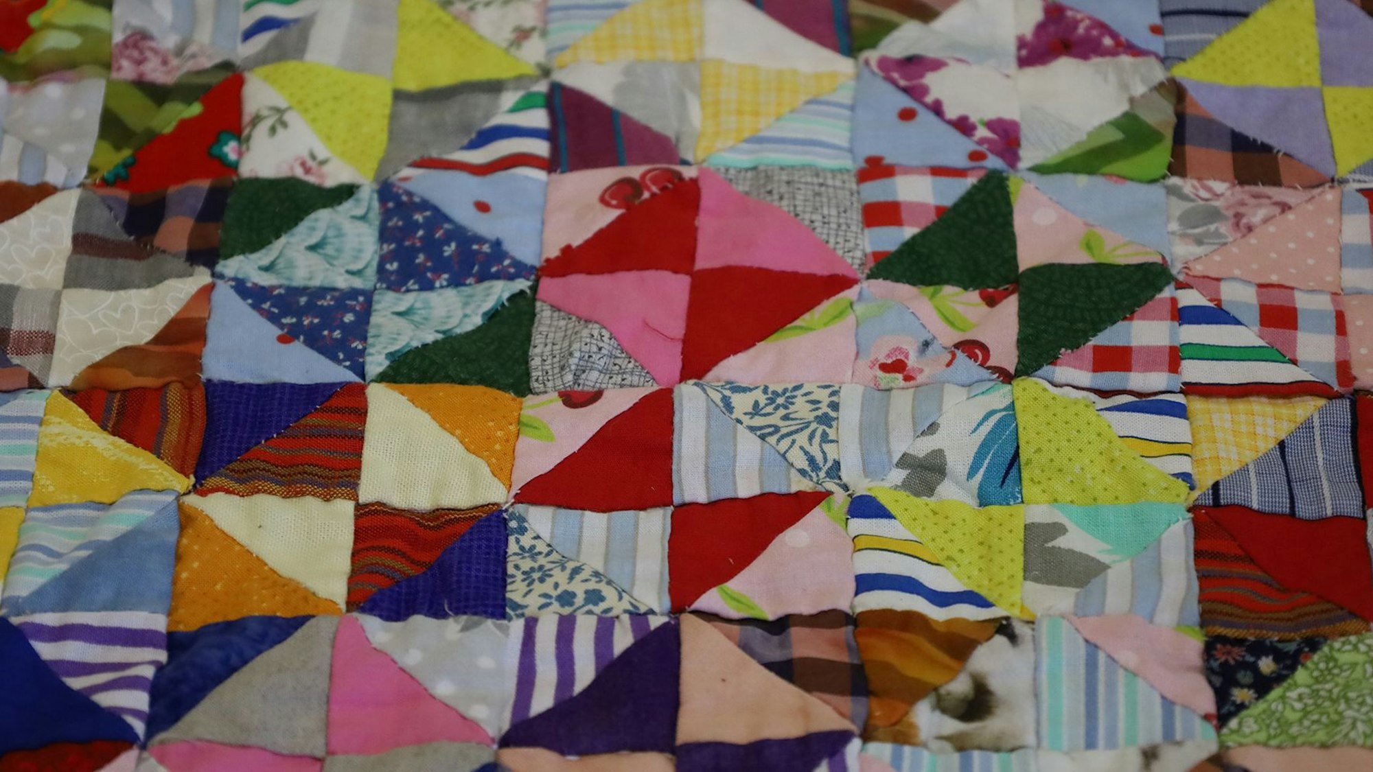 Das Bild zeigt einen Ausschnitt einer Patchwork-Decke, die aus Hunderten von kleinen, aneinander genähten Stoffstücken besteht.
