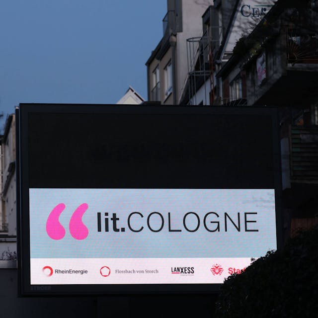 Werbung für die lit.Cologne leuchtet an einer Hausfassade in Köln.