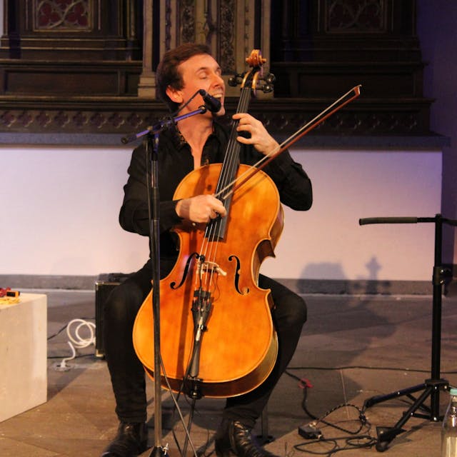 Ein Mann spielt Cello in einer Kirche.