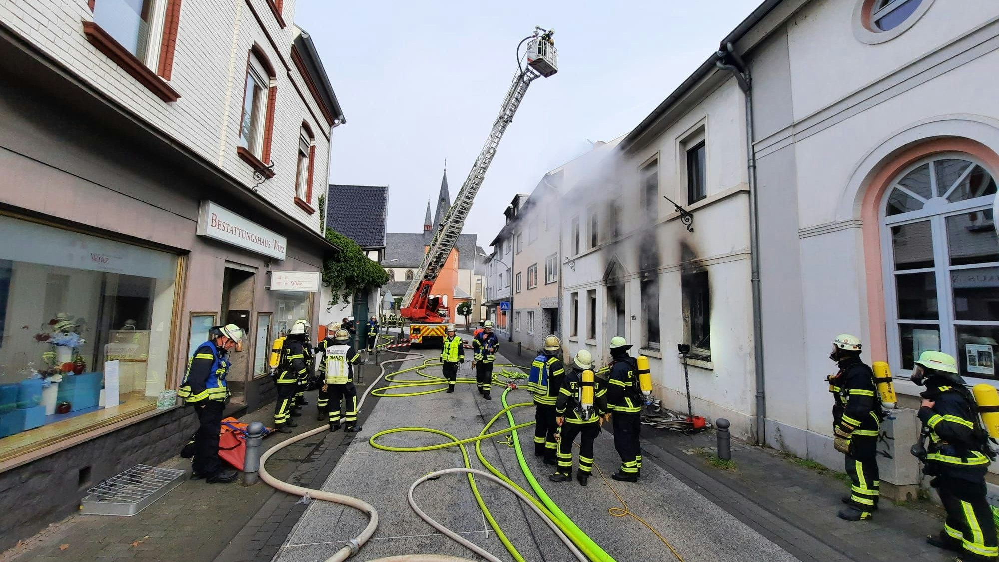 Feuerwehrleute und eine Drehleiter sind auf der Hauptstraße Niederdollendorf im Einsatz.