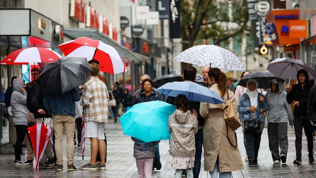 Menschen mit Regenschirmen laufen über die Fußgängerzone der Hohe Straße.&nbsp;