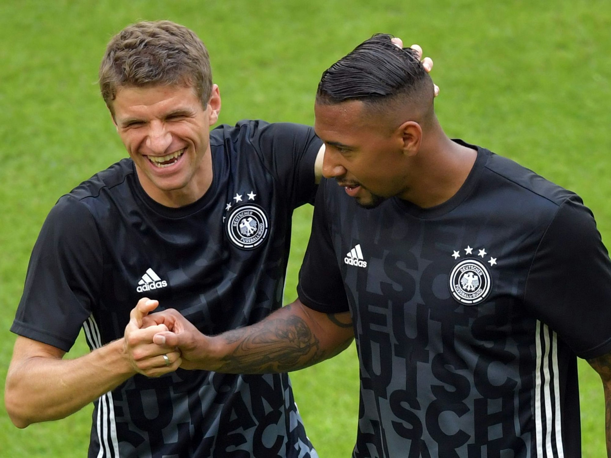 Müller und Jérôme Boateng in Aufwärmkleidung scherzen miteinander.