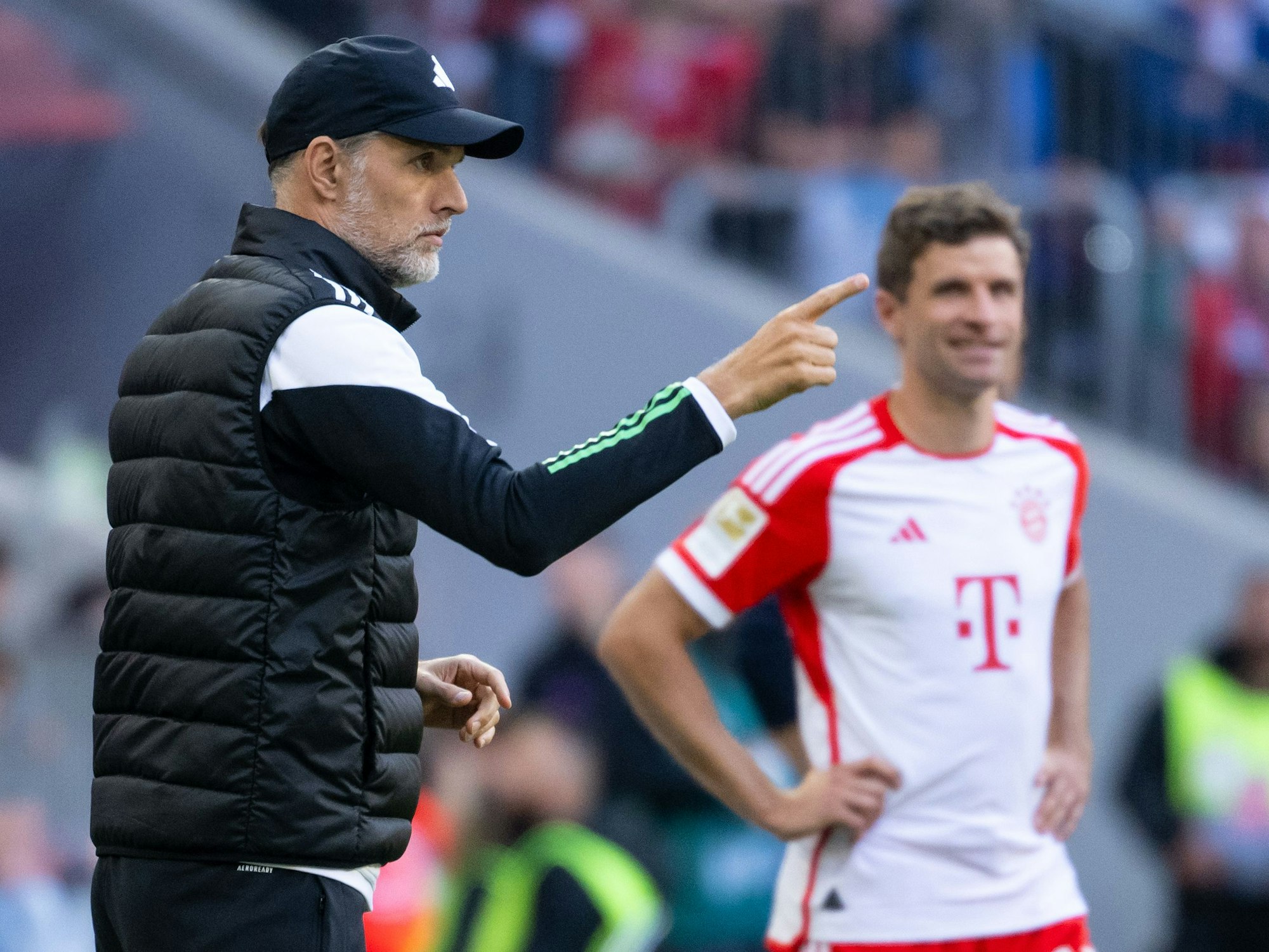 Thomas Tuchel zeigt seinen Spielern beim Spiel gegen den VfL Bochum etwas an. Thomas Müller grinst im Hintergrund.