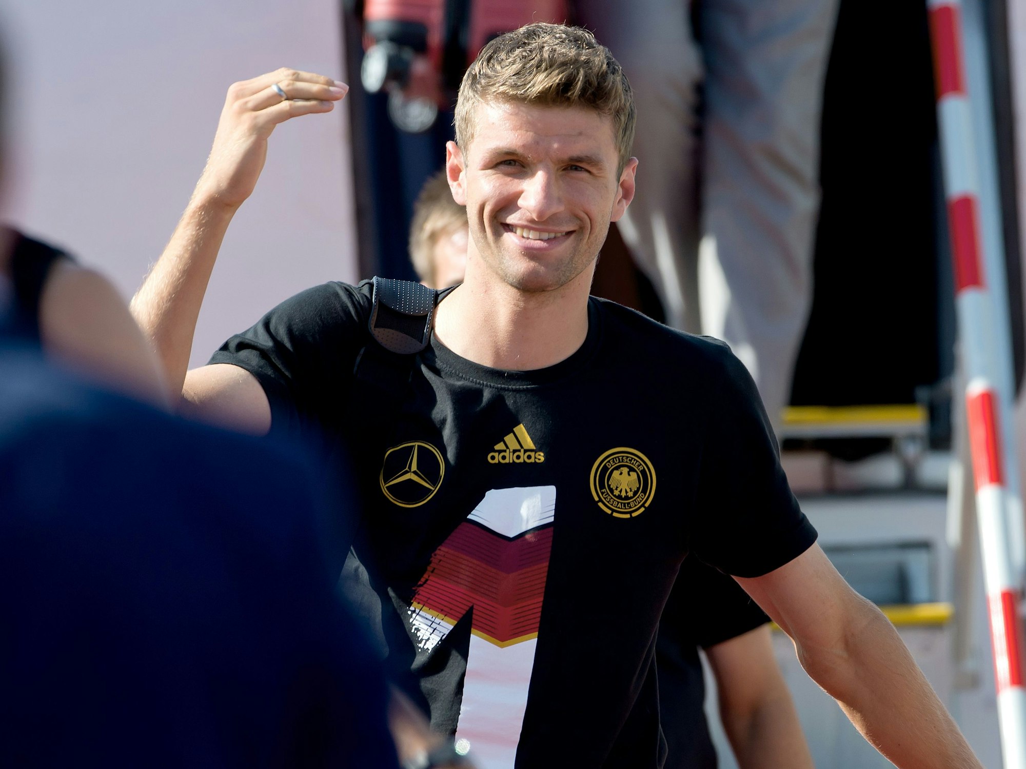 Nationalspieler Thomas Müller winkt am Flughafen in München nach seiner Ankunft aus Berlin. 