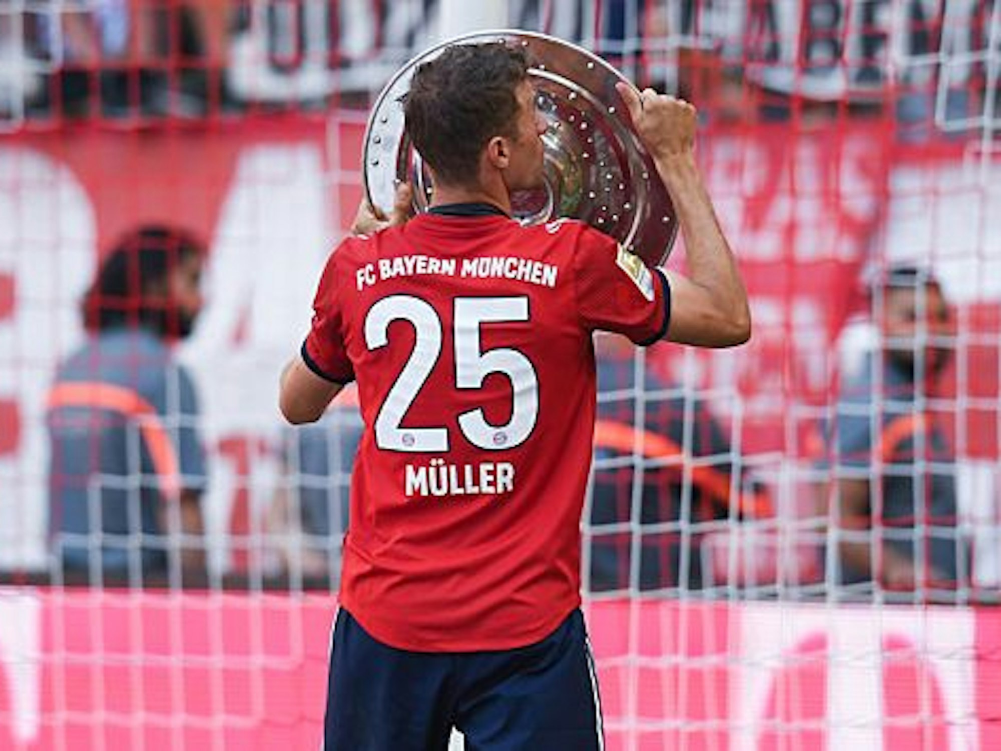 Müller feiert im Trikot mit der Meisterschale auf dem Spielfeld.