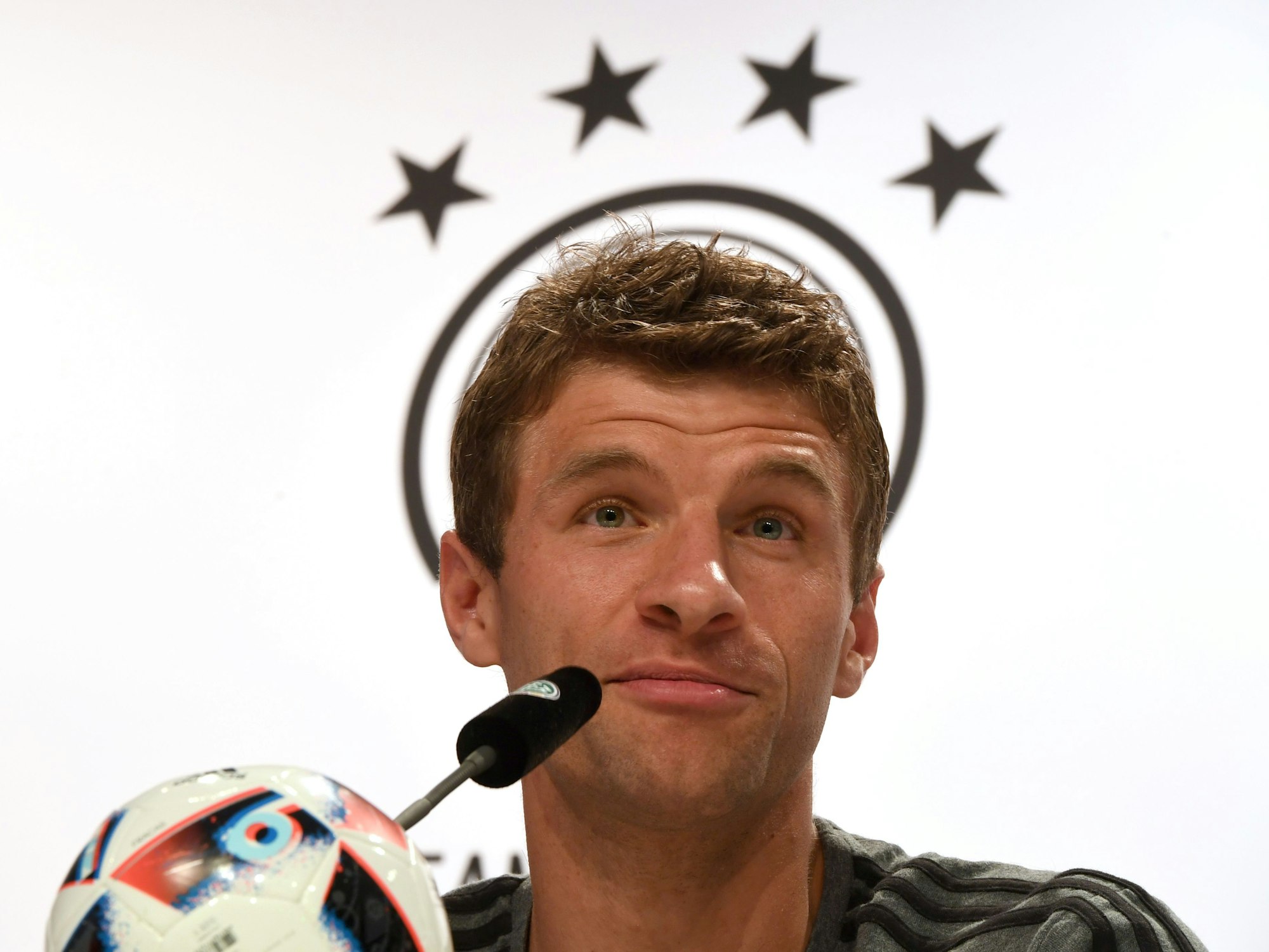 Thomas Müller spricht auf einer Pressekonferenz des DFB, er hat ein leichtes Lächeln im Gesicht.
