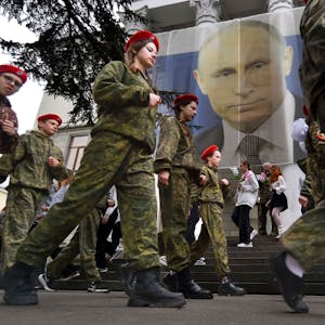 17. März 2023:&nbsp; &nbsp;Uniformierte Jugendliche marschieren in Jalta anlässlich einer Aktion zum neunten Jahrestag der Krim-Annexion an einem Bildnis des russischen Präsidenten Wladimir Putin (im Hintergrund) vorbei. Foto: U