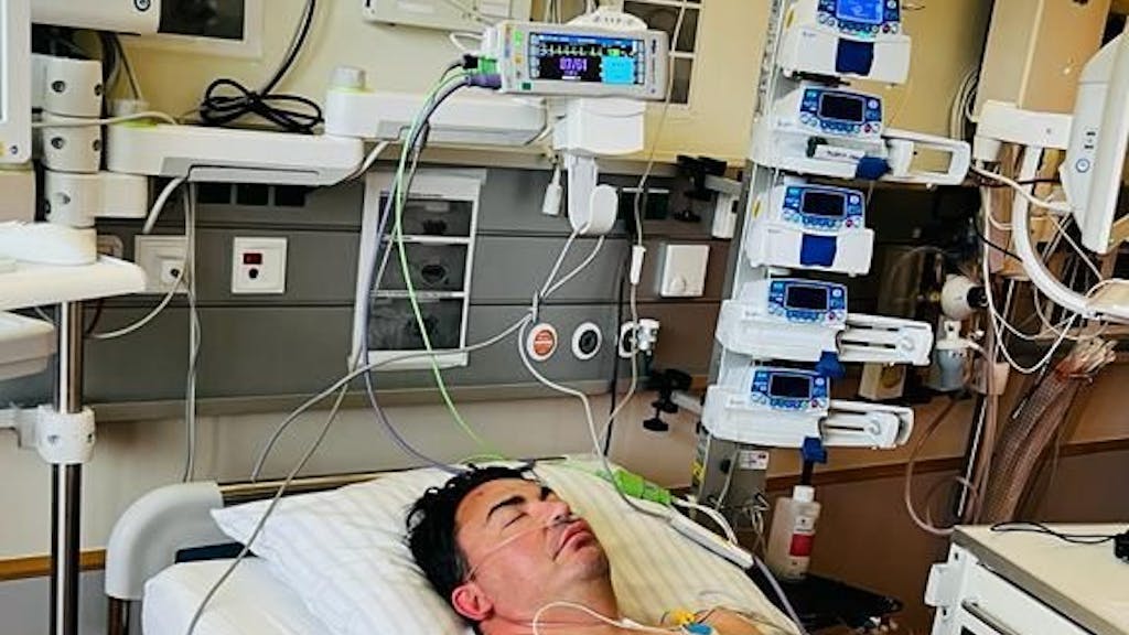 Matthias Mangiapane liegt mit geschlossenen Augen im Krankenhausbett.