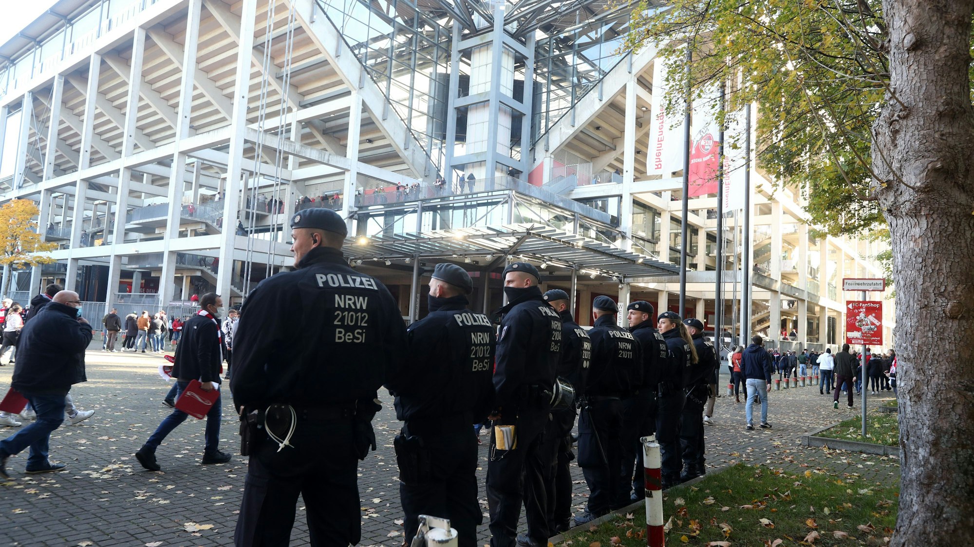 Etwa acht Einsatzkräfte der Polizei stehen vor dem Rhein-Energie-Stadion in Köln und überwachen die Besucherinnen und Besucher.