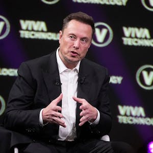 Elon Musk im Anzug und Hemd vor einer Leinwand mit der Aufschrift "Viva Technology"