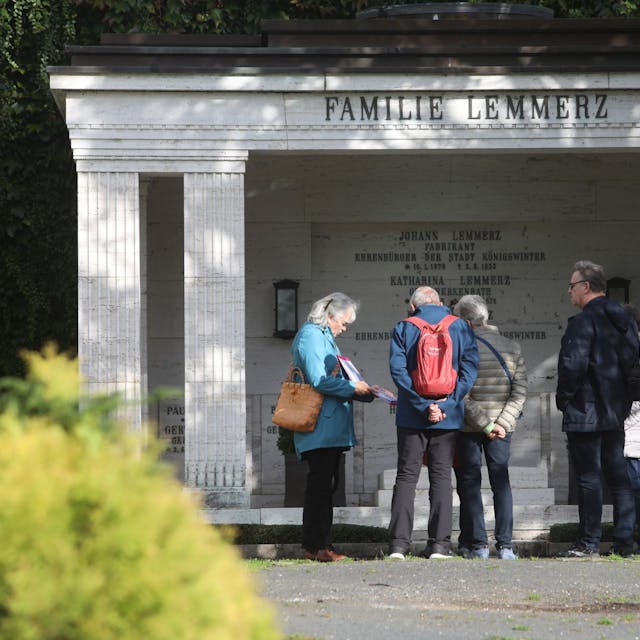 Eine Gruppe von Menschen stehen vor dem großen Familiengrab der Familie Lemmerz.