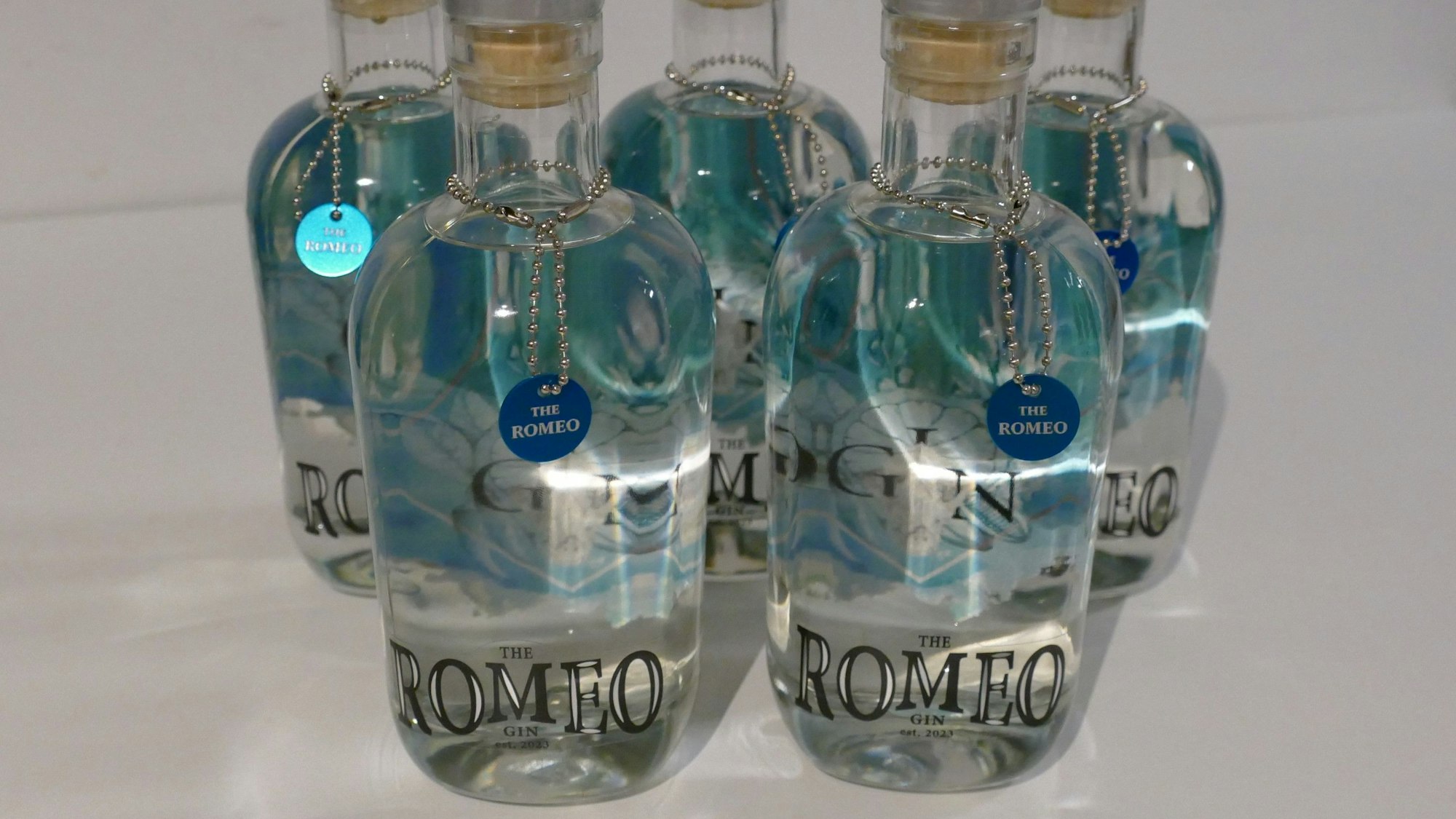 Flaschen mit durchsichtigem Inhalt und blauen Etiketten stehen vor einem weißen Hintergrund.