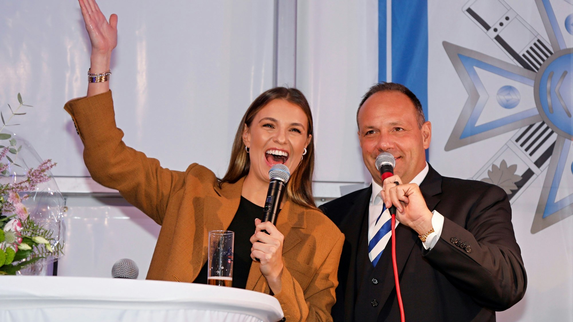 Moderatorin Laura Wontorra mit Björn Griesemann auf einer Bühne. Beide grinsen und rufen Kölle alaaf.