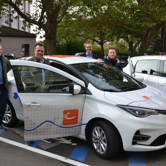Sacha Reichelt und Vertreter des Kreises Euskirchen, der SVE, der e-regio und des Car-Sharing Anbieters Cambio präsentieren ein E-Auto des Typs Renault Zoe.