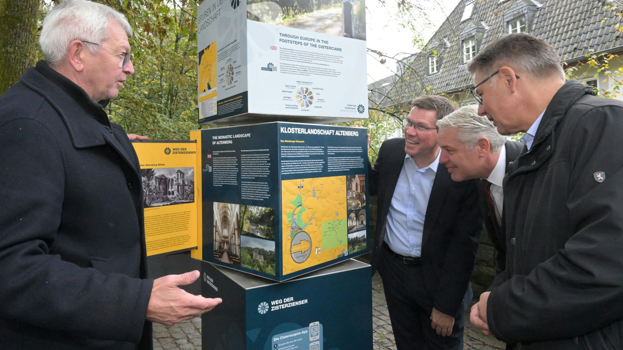 Unter anderem Landrat Stephan Santelmann und Bürgermeister Robert Lennerts schauen auf die Infotafel des Wanderweges.