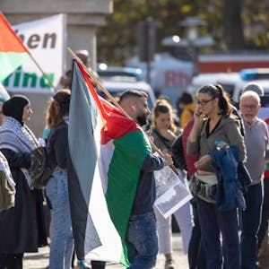 Menschen mit Palästina-Fahnen stehen auf dem Kölner Heumarkt