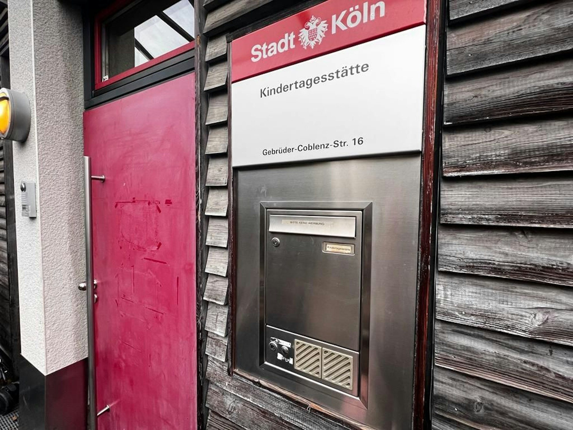 Neben einer Haustür hängt ein Schild, das auf eine Kindertagesstätte der Stadt Köln verweist.