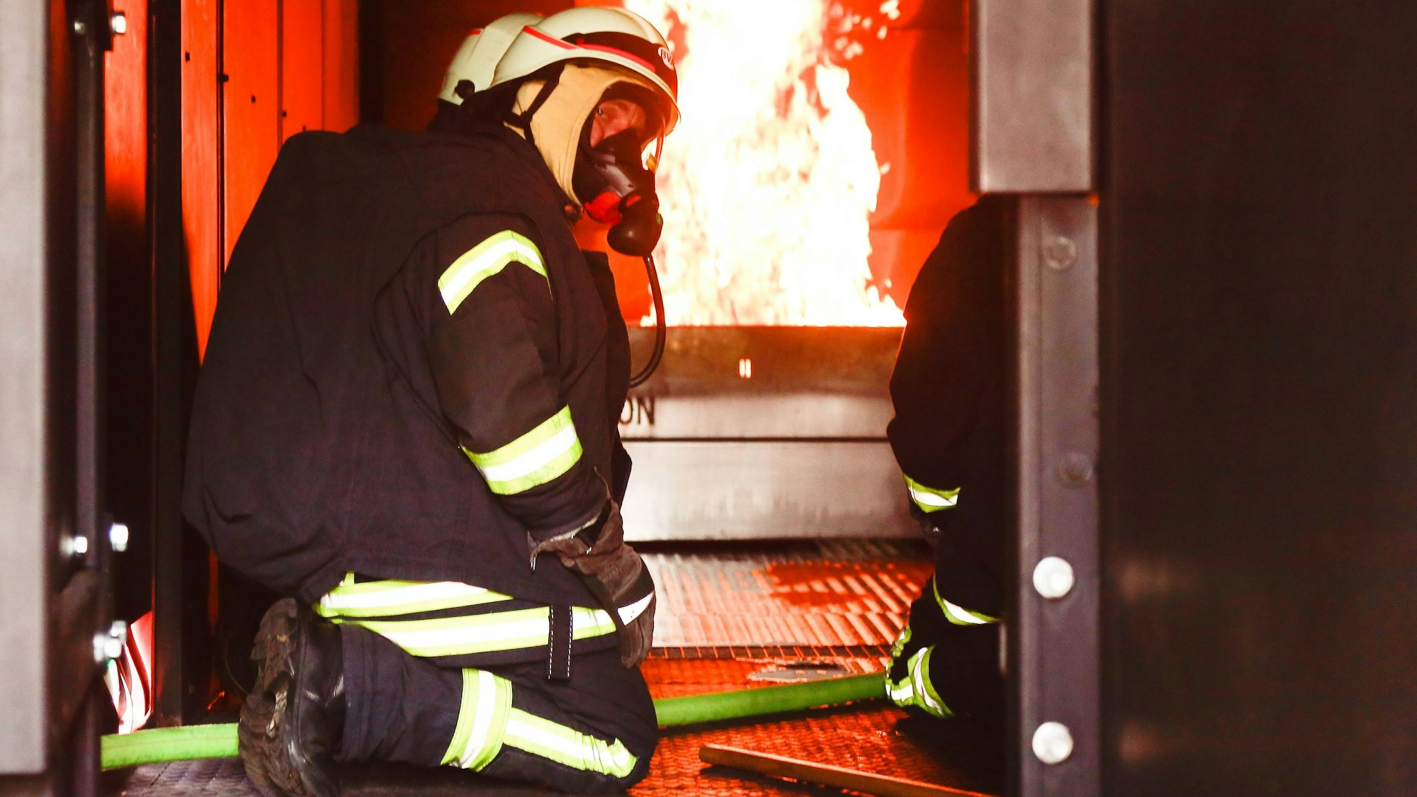 Feuerwehrleute mit Atemschutzmaske im Brandübungscontainer der Feuerwehr Köln.